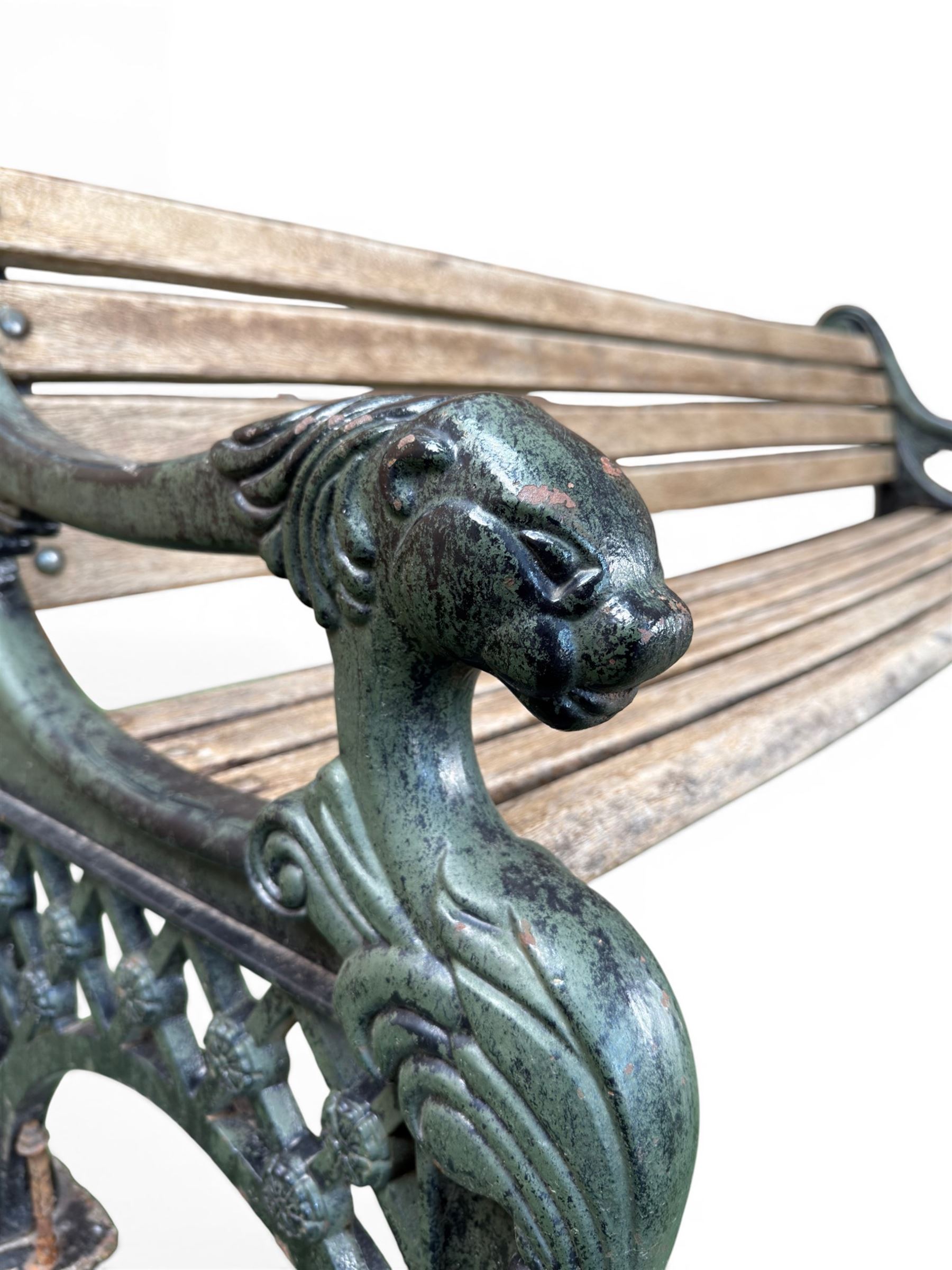 Neoclassical design cast iron and oak slatted garden bench, the twin end supports in the form of a Sphinx with acanthus carved knees and large paw feet, the pierced lattice bracket with Yorkshire rose motifs