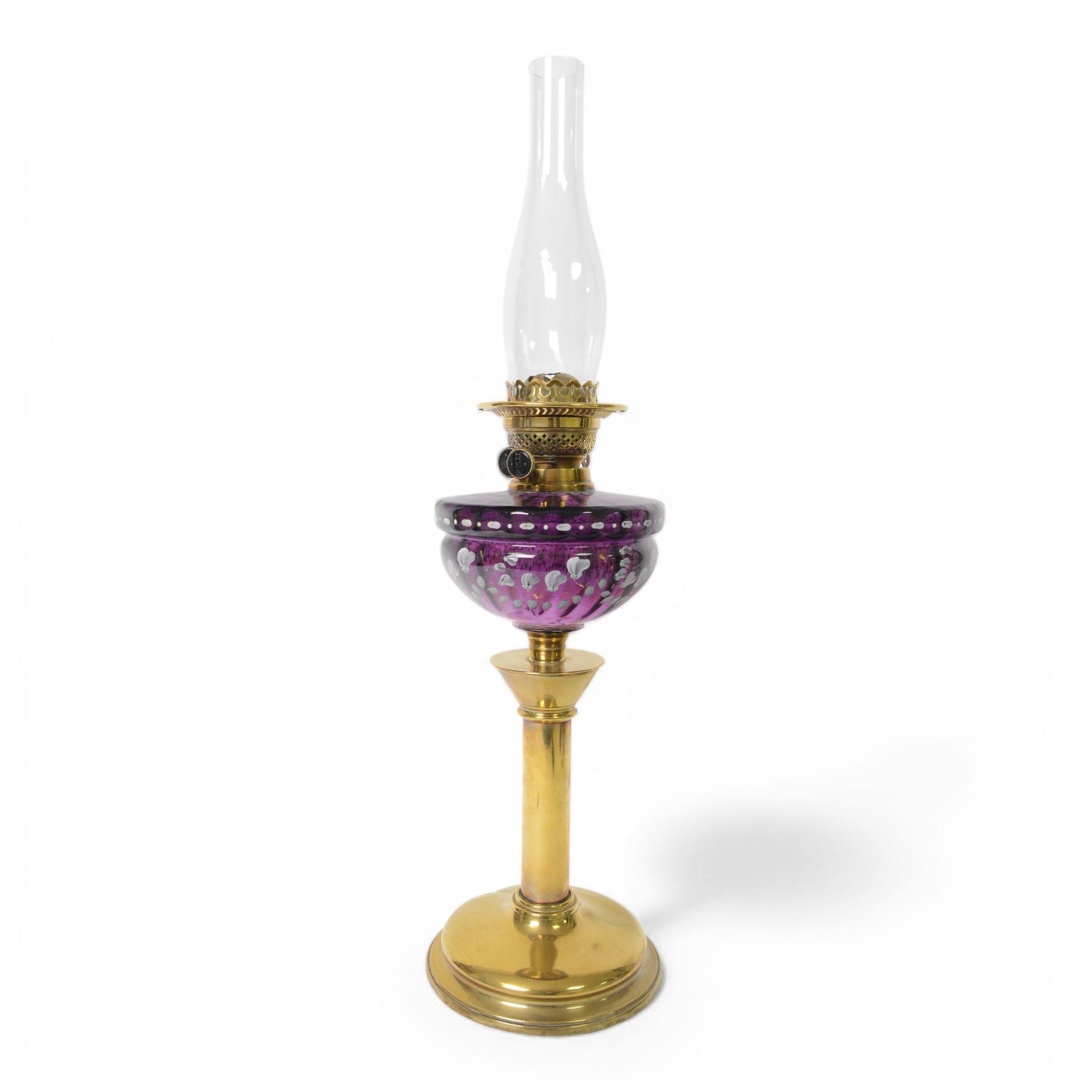 Victorian oil lamp, the brass base supporting a floral enamelled amethyst glass reservoir, duplex burner, and clear glass chimney, overall H69cm