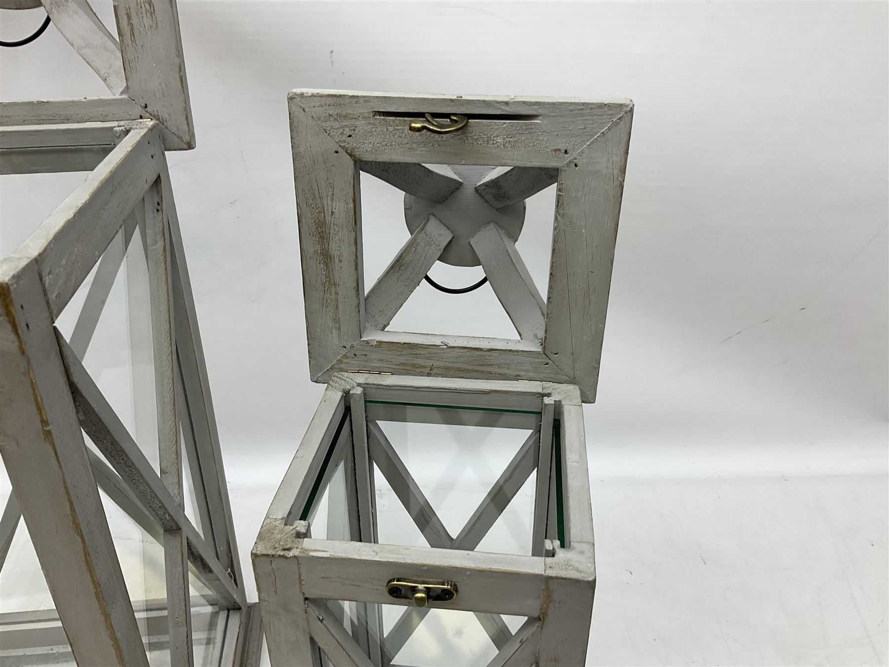 Two wooden lanterns with four glass sides, loop handles and open tops, largest example 58cm