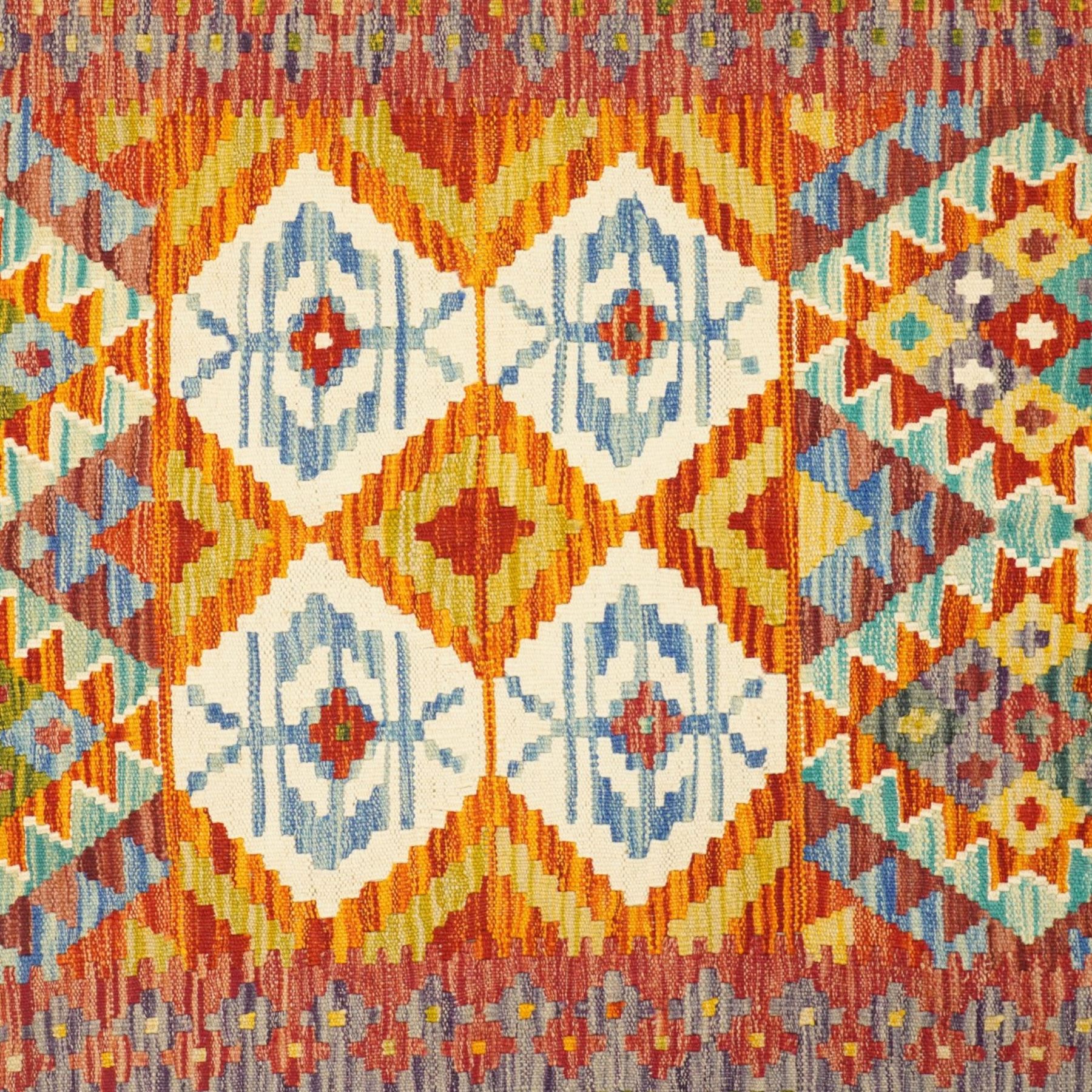 Afghan Chobi flatweave kilim, with a repeating stepped diamond medallion design in ivory, green, rust, teal, purple, indigo, and framed by chevron and geometric borders