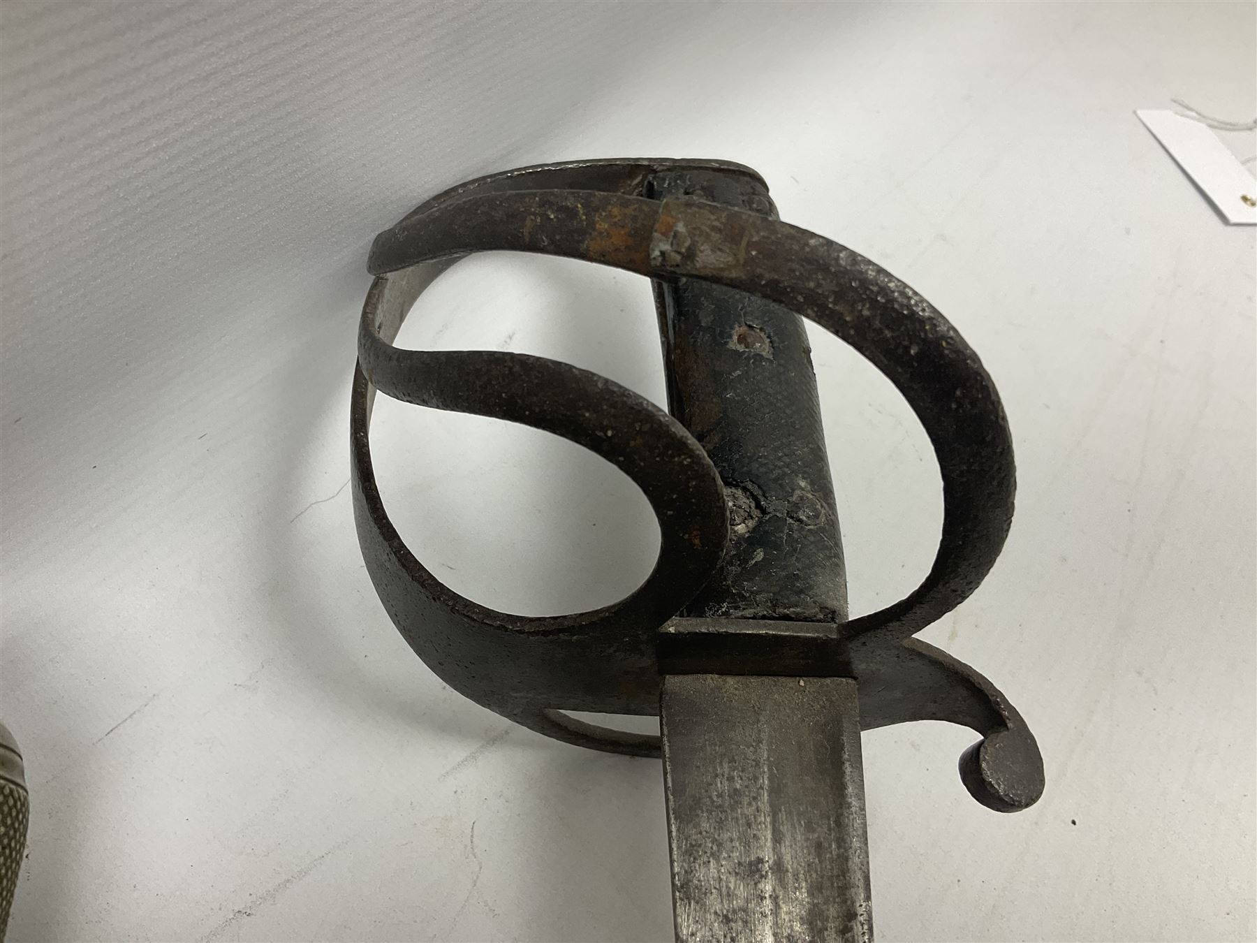 George V British Army 1897 pattern officers sword with plain 82cm fullered steel blade, pierced  basket hilt with George V cypher and wire bound leather grip with chequered backstrap; in leather covered field service scabbard L101cm overall; and another officer's sword in relic condition lacking scabbard (2)