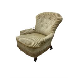 Late 19th century low seat armchair, upholstered in button back striped fabric with sprung seat, on front turned supports with castors