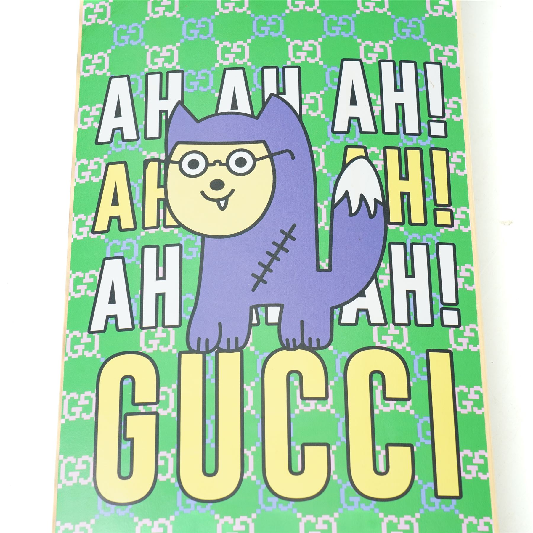 Gucci x Palace skateboard, Spring/Summer 2021, green GG monogram wood deck with multicolour ‘AH AH AH! GUCCI’ lettering and cartoon character mascot motif, fitted with Gucci-branded metal trucks and red and cream wheels, model no. 689103 JCGMN, presented with original GG monogram drawstring dust bag, protective sleeve, outer box and accompanying cards, Skateboard L81cm W20cm