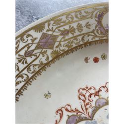 Large and impressive 18th century Meissen dish, finely painted with a chinoiserie scene to a central shaped reserve, depicting figures and attendants engaged in various pursuits, the reserve with gilt scrollwork edge, filled with Böttger lustre and detailed with iron red scrollwork, surrounded by flower heads, the rim with four quatrofoil Kauffahrtei scene panels of merchants and figures by a quayside in purple monochrome, with gilt scroll border, with under glazed blue crossed swords mark, and gilt gilders mark, D39cm
