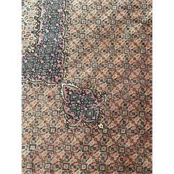 Persian Bidjar peach ground carpet, central pole medallion enclosed within lozenge field and spandrels, decorated all over with small Heratti motifs, the main border with trailing pattern decorated with stylised plant and Boteh motifs, within two triple band guard stripes with repeating flower head decoration 