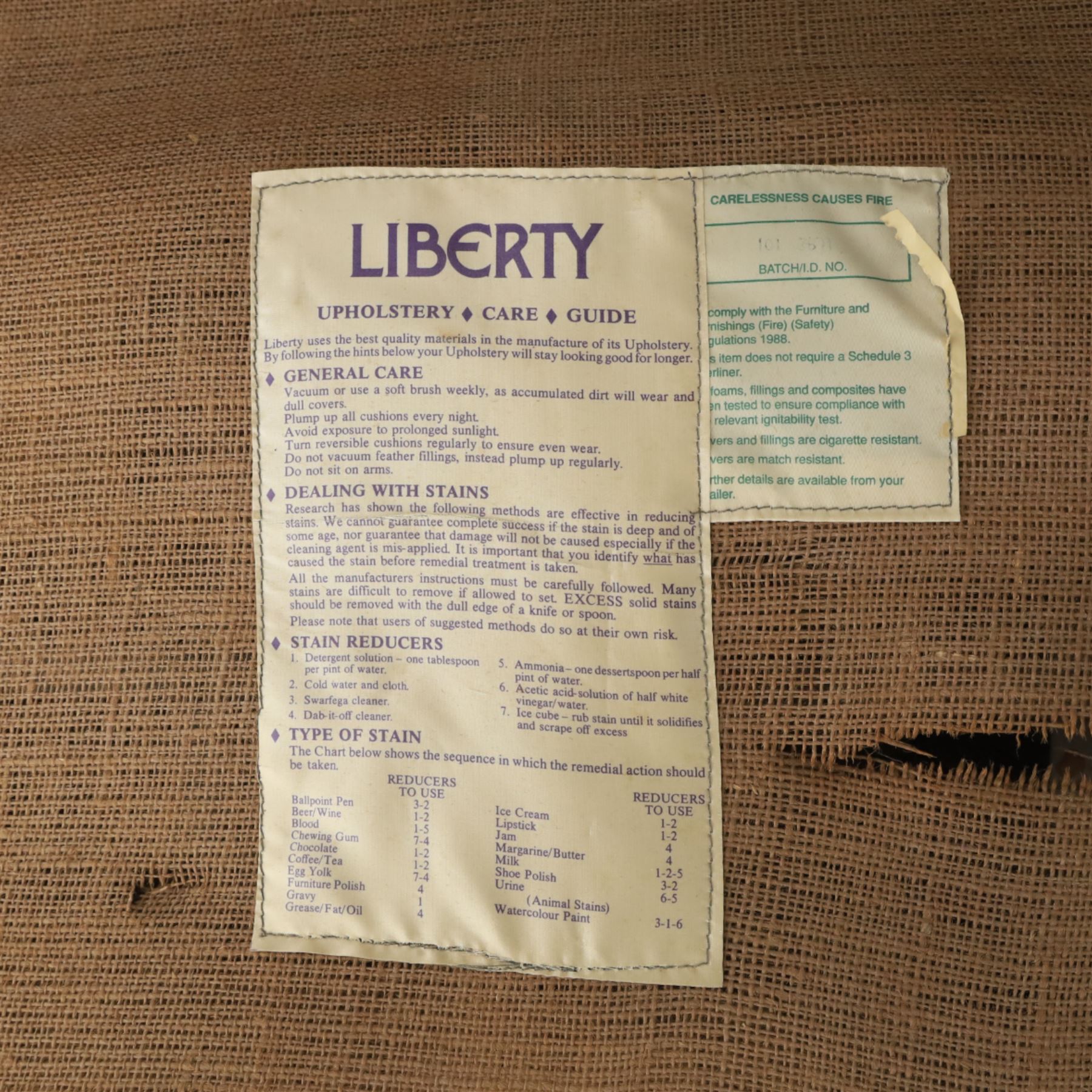 Late 20th century Liberty upholstered two seater sofa, the shaped back and arms with deep buttoned upholstery, covered in Art Nouveau fabric with stylised floral and foliate motifs, loose scatter cushions en suite, raised upon turned tapering front supports and swept rear legs