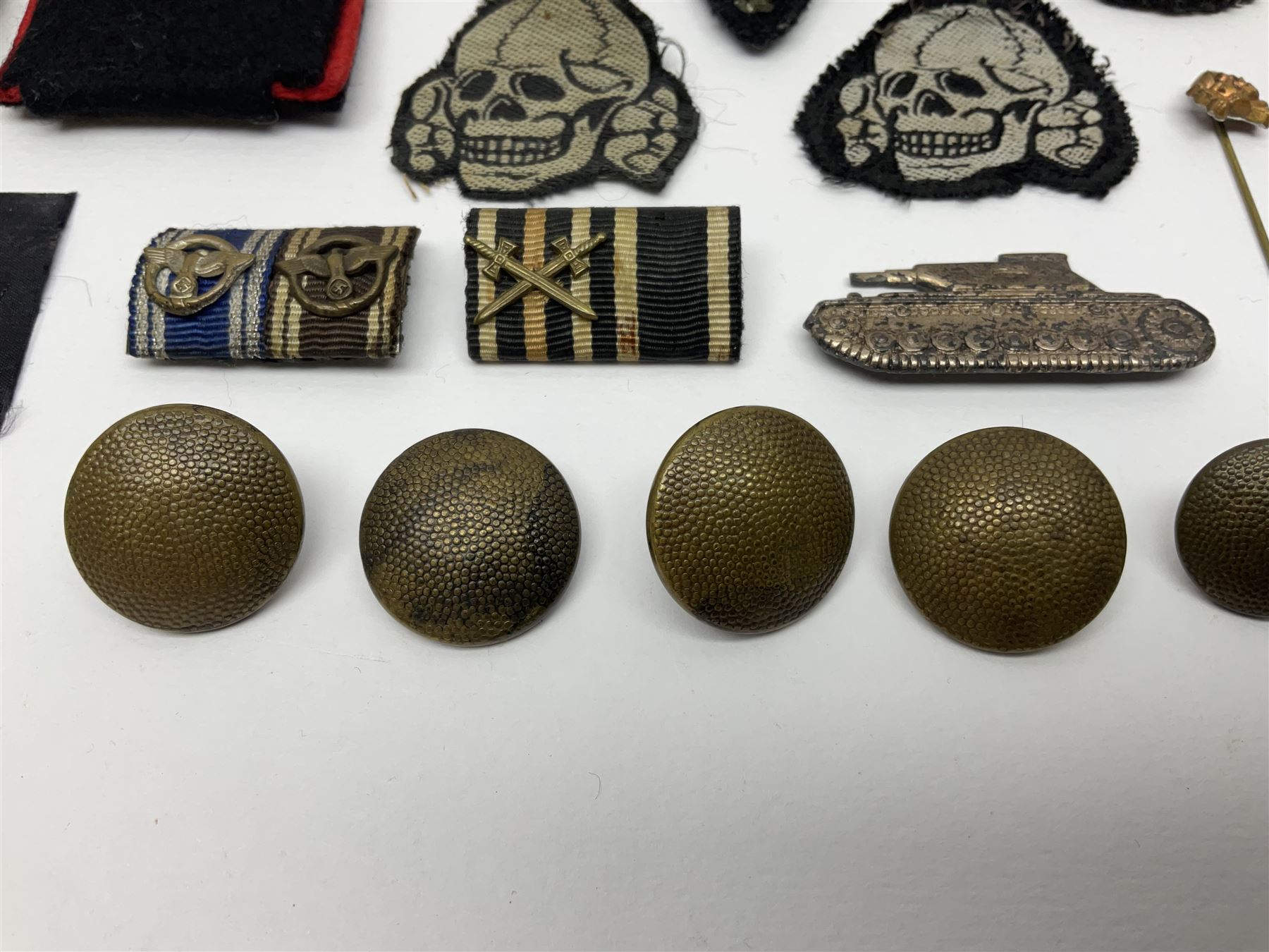 Collection of eleven German metal and cloth badges and uniform buttons including driver's badge, two 'SS' fabric skulls, private's shoulder tabs, Police cloth badge, tank destruction badge, medal bars and ribbon etc; most WW2 period