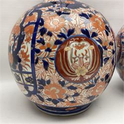 Pair of large 19th century Japanese Imari porcelain bottle vases, painted with shaped reserves of peonies, chrysanthemums and prunus blossom, each H46cm