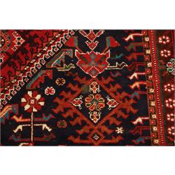 Persian tribal hand-knotted rug, crimson ground, madder field with central stepped lozenge medallion with scattered floral and geometric spandrels with rosette border 