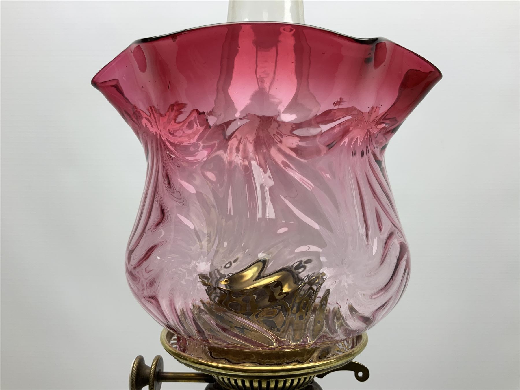 20th century Hawksworth, Eyre & Co silver plated oil lamp, the octagonal stepped base with engraved dedication, leading to an octagonal column supporting a faceted clear glass reservoir, Hinks Duplex burner, clear glass chimney, and cranberry glass shade, overall H71.5cm