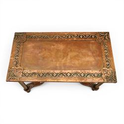 Arts and Crafts copper mounted coffee table, rectangular top with embossed foliate border and stylised corner motifs, studwork detail, on cylindrical supports united by pierced shaped stretcher with applied flowerhead bosses