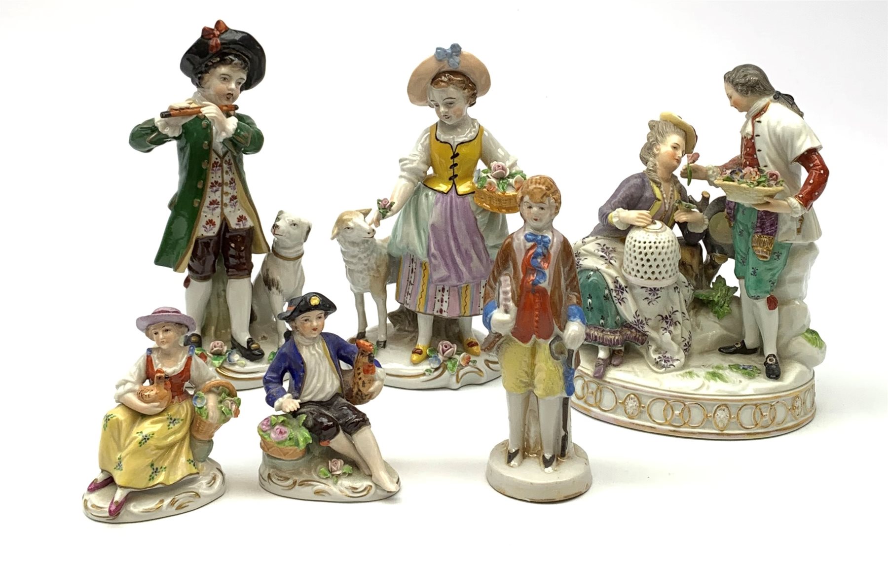 A pair of Sitzendorf porcelain figures, the first modelled as a boy playing the flute, with dog seated at his feet, the second modelled as a girl with basket of flowers and sheep stood beside her, each upon oval gilt detailed base, each with printed mark beneath, H17cm, together with a Naples figure group, a pair of small Sitzendorf figurines, and a later example marked Japan. (6). 