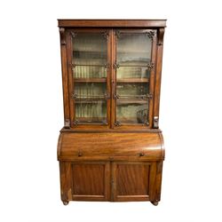 Mid-19th century mahogany secretaire bookcase, plain frieze over two astragal-glazed doors with foliate motif mouldings, cylindrical barrel roll top with slide revealing small drawers, pigeon holes and adjustable writing surface, double panelled cupboard below, on bun feet