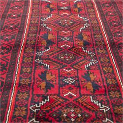 North east Persian Baluch hand-knotted runner, crimson ground with a vertical column of hooked lozenge medallions flanked by stylized leaf motifs within multiple geometric borders of rosettes and angular vines  
