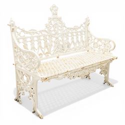 Victorian revival heavy cast iron garden bench, ornate back rest with scrolls, floral motifs and central crest, pierced lattice seat, curved arms and decorative legs, painted in antique white, in the Gothic Coalbrookdale style