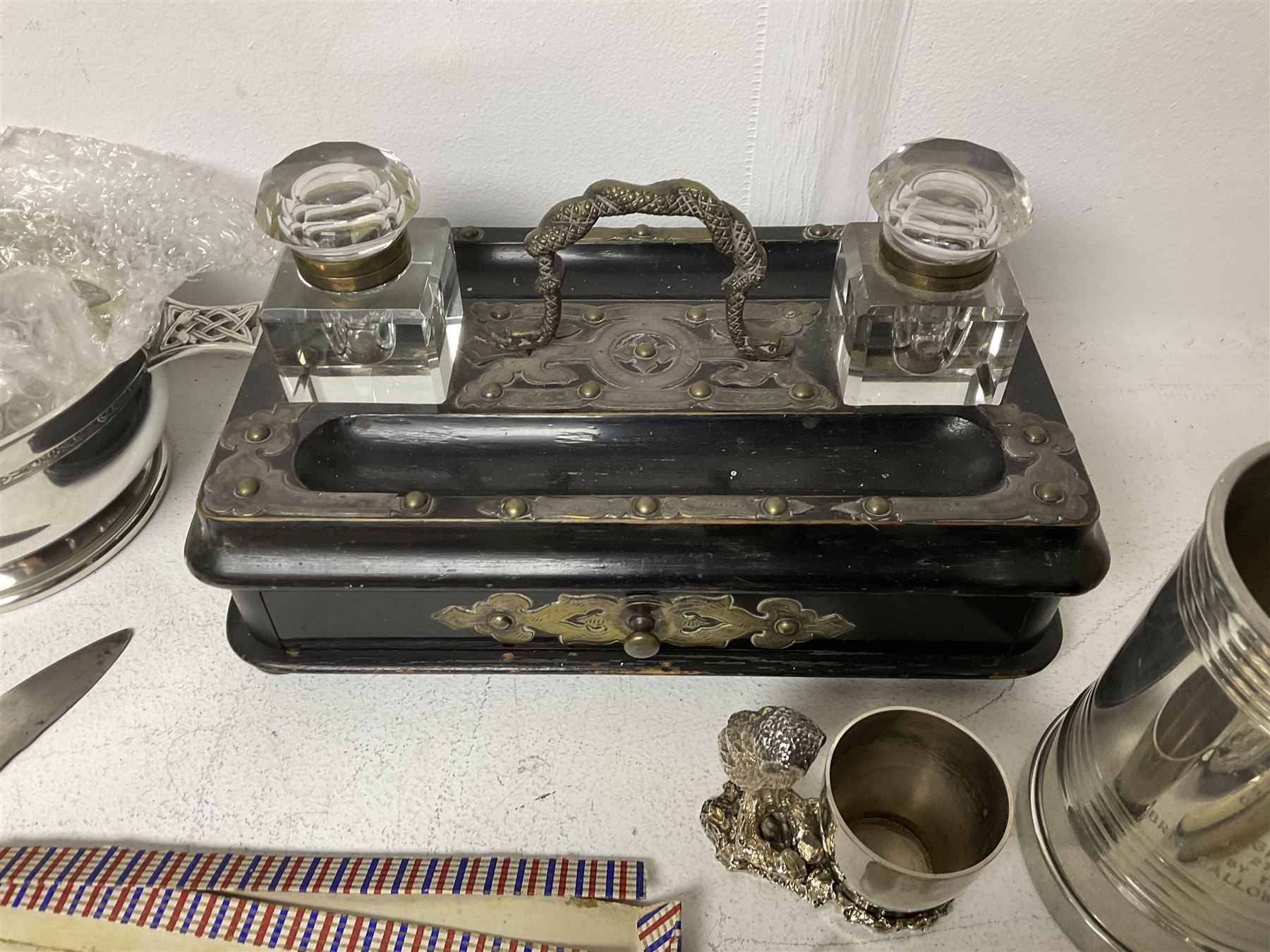 Victorian ebonised wooden desk stand, with brass mounts and two glass inkwells, together with two pewter tankards with Masonic engravings, two pewter quaiches, horn handled carving set, the fork with silver mounts and a collection of other metalware