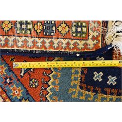 Caucasian Kazak vermillion ground rug, the sectioned field decorated with three geometric lozenge medallions surrounded by stylised plant and animal motifs, the multiple guard bands with repeating geometric design