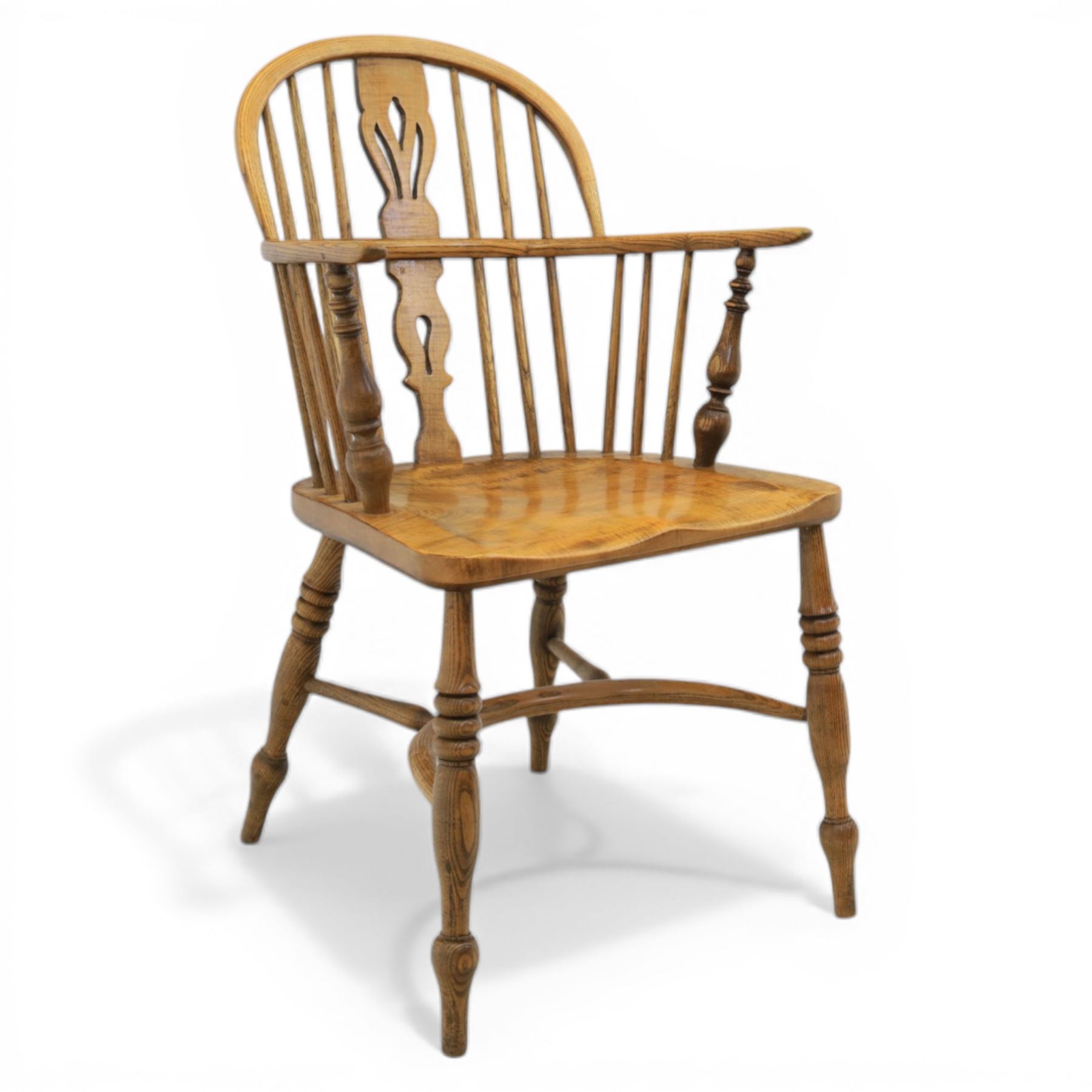 Late 20th century elm and beech low back country Windsor armchair, the arched hoop back with central pierced splat and turned spindles, shaped arm rail on turned supports, saddle seat, raised on turned legs united by a crinoline stretcher