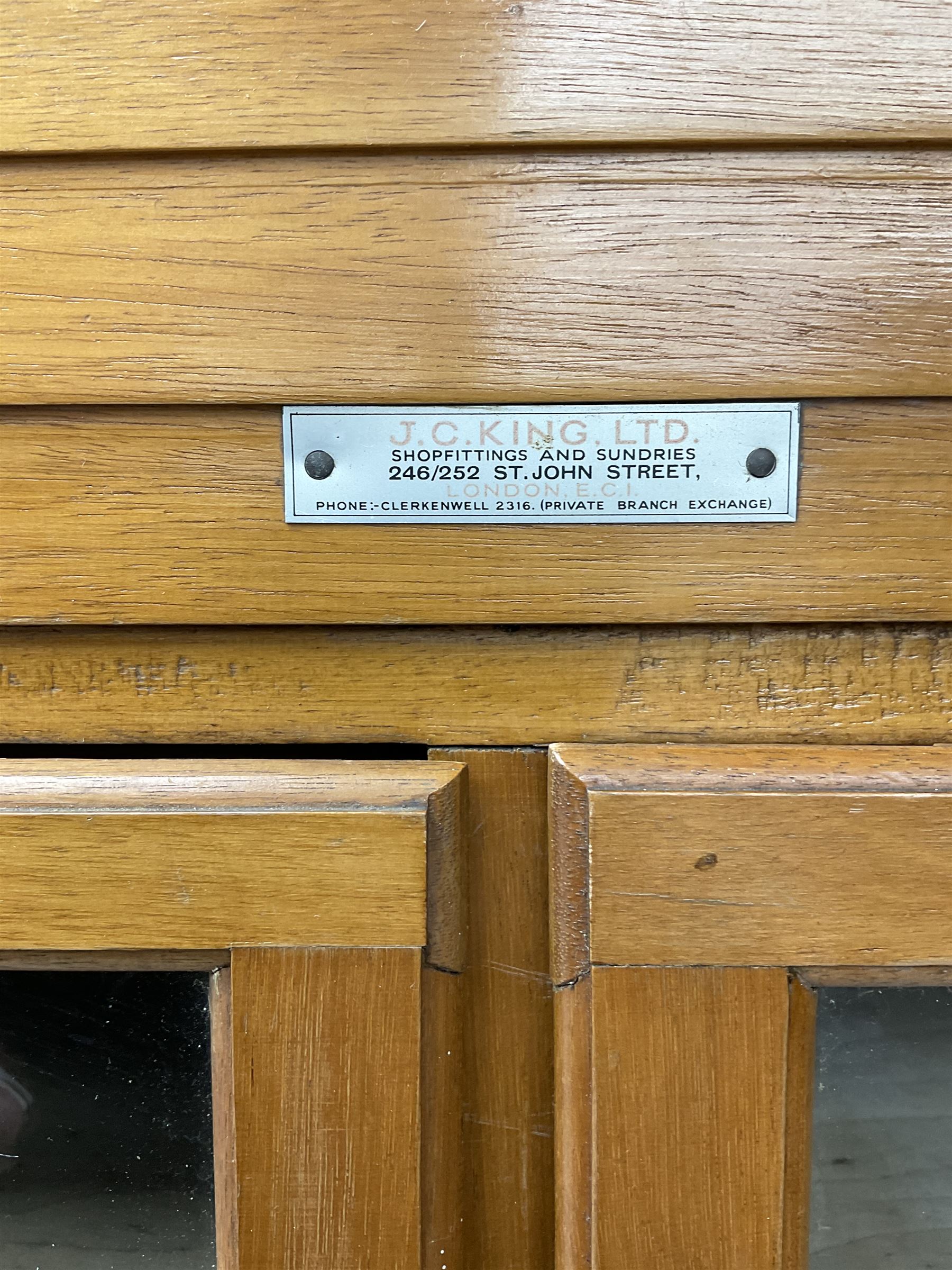 Haberdashery display cabinet with plaque ‘J.C. King Ltd, Shop fittings & Sundries, St John's Street London’, sixteen glazed front short drawers, above four deep drawers