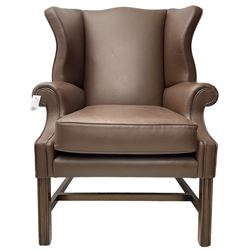 Georgian design wingback armchair, rolled arms over loose seat cushion, upholstered in chocolate brown leather, on square moulded supports united by H-stretcher