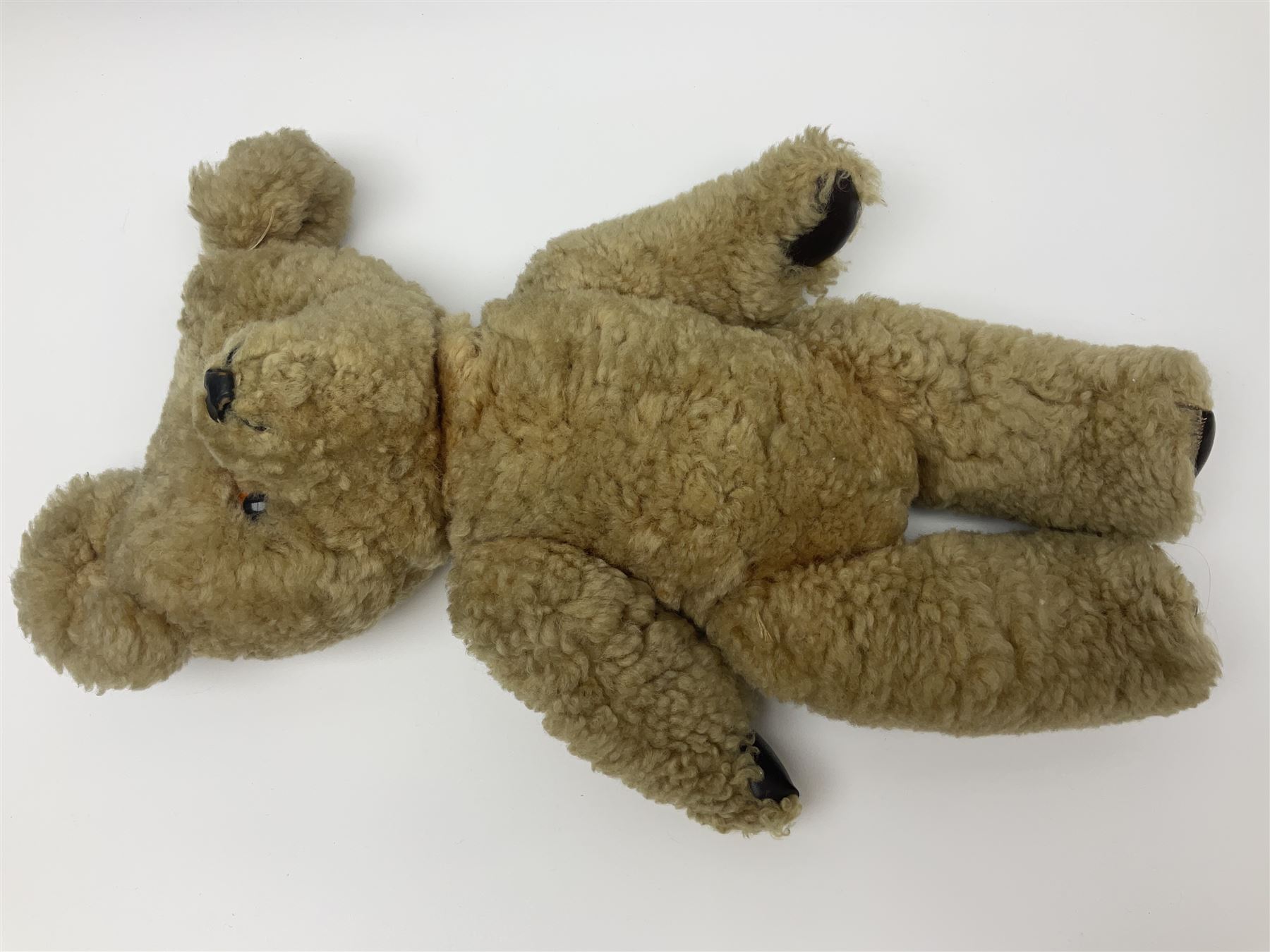 1950s sheepskin plush covered teddy bear with musical movement, the revolving head with applied eyes, leather nose and stitched mouth, jointed limbs with leather pads H50cm