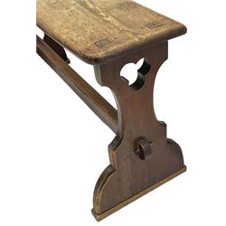 Late Victorian ecclesiastical pitch pine side table, rectangular bow-front top, on shaped end supports pierced with quatrefoils, united by pegged stretcher 