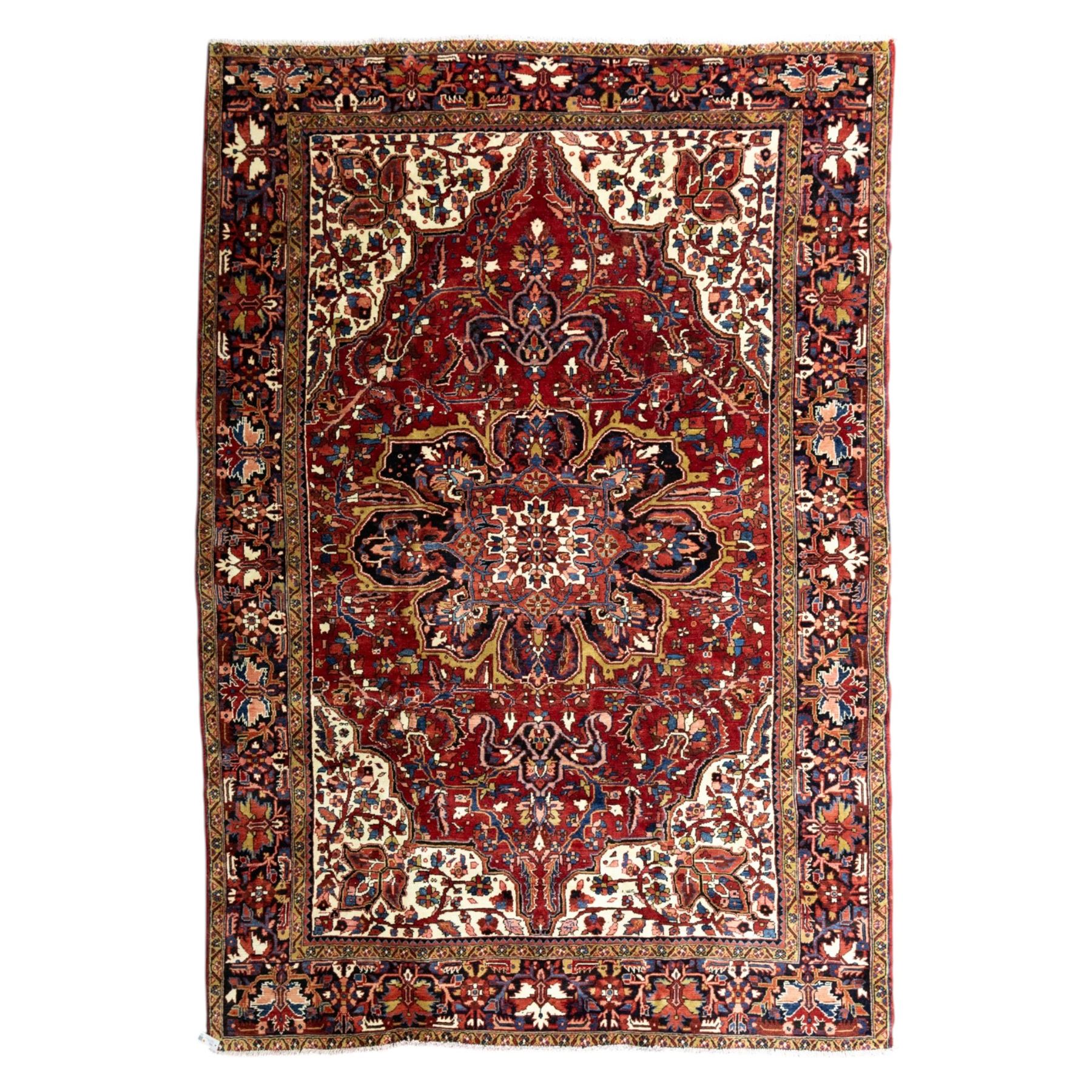 North West Persian Ahar hand-knotted carpet, madder red ground, with a large central shaped floral medallion with pendants, surrounded by angular scrolling foliate motifs incorporating rosettes, palmettes and stylised flowerheads, enclosed by ivory spandrels and a dark navy border with repeating geometric floral motifs and meandering vines, flanked by narrow patterned guard stripes, with cotton fringes