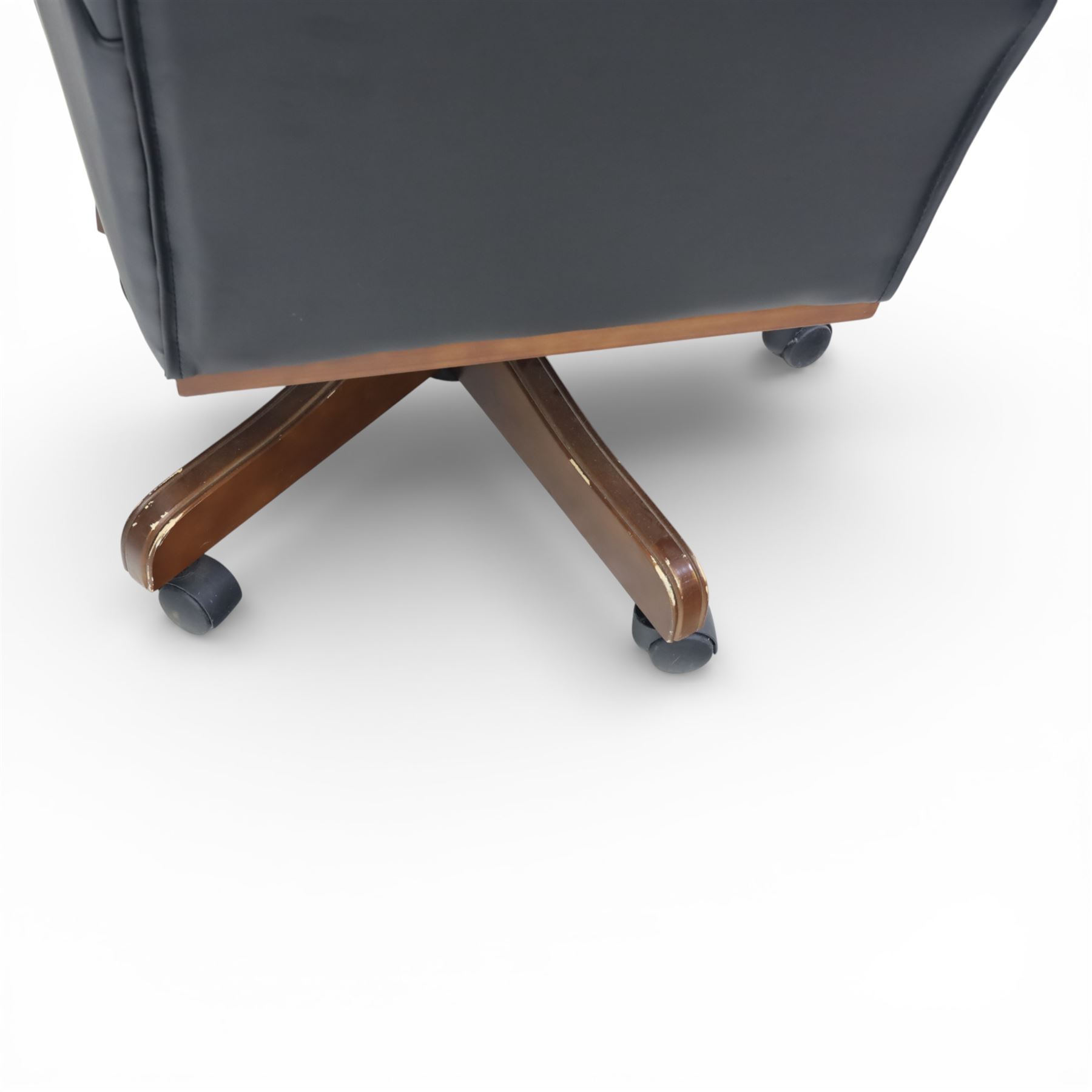 Chesterfield style desk chair upholstered in black, brass studded trim with tall button backed seat, with faux wooden base raised upon castors