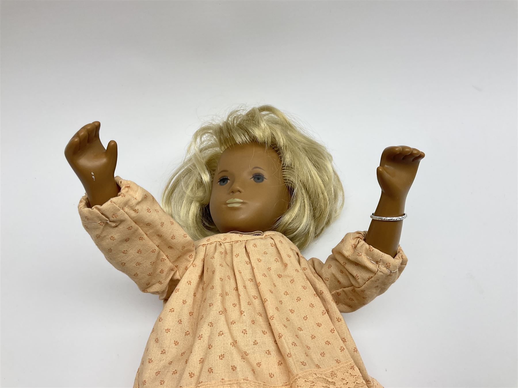 Sasha Morgenthaler vinyl doll, the girl's head with painted blue eyes and lips and short blonde hair, the jointed body donning a peach floral dress with matching underclothes, unmarked, H41cm