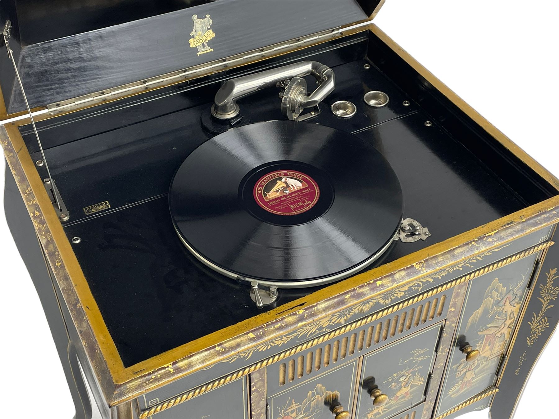 Early 20th century Chinoiserie lacquered gramophone cabinet, the lid decorated with raised gilt work, traditional landscape and figural scenes, fitted with 'Apollo' 'No. 114' gramophone, cupboards below, on cabriole supports