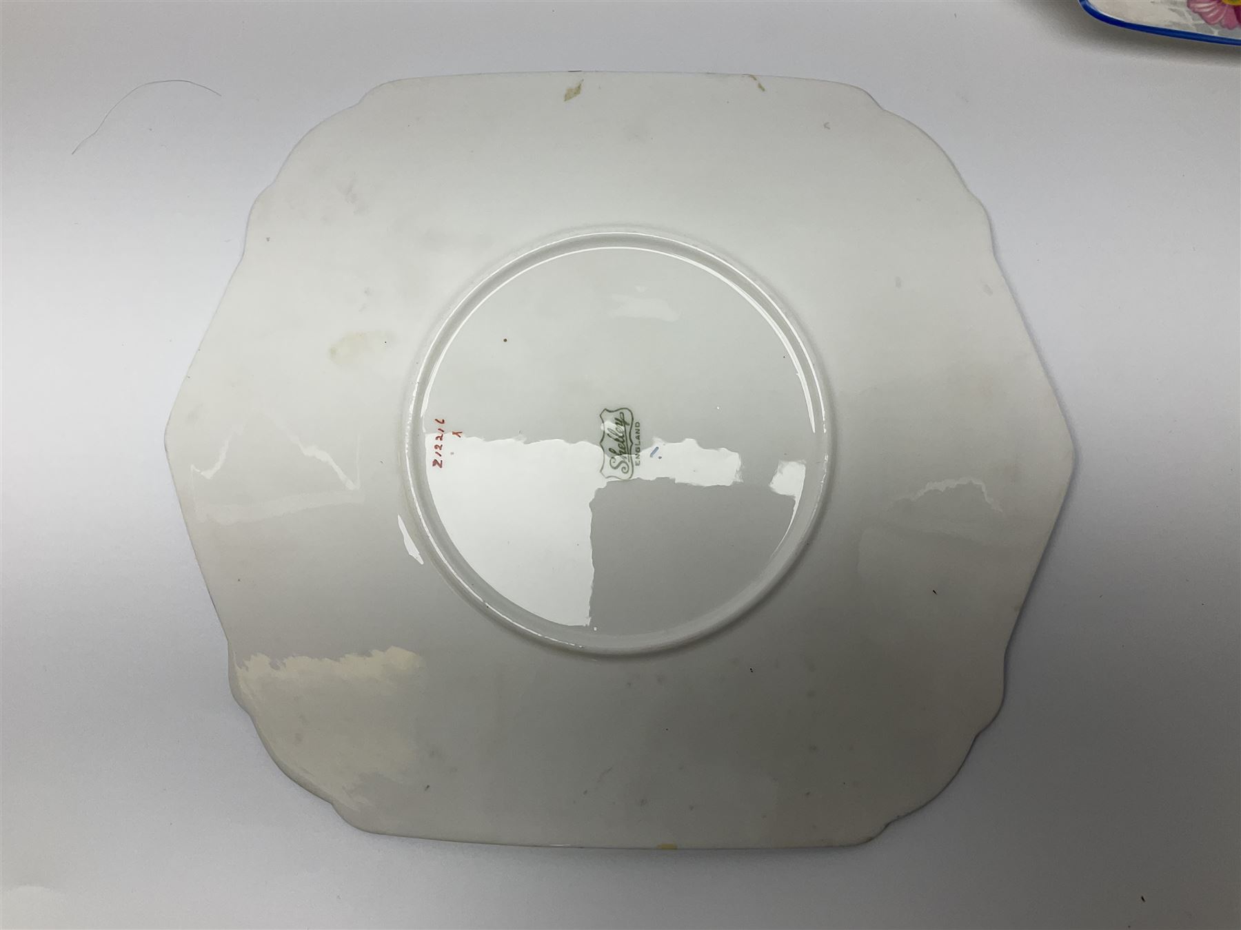 Shelley Strand shaped tea wares, decorated with blue and pink daisies upon a white ground, comprising four teacups, four saucers, three tea plates, milk jug, sugar bowl and cake plate, all with printed green mark beneath and painted pattern no 12216