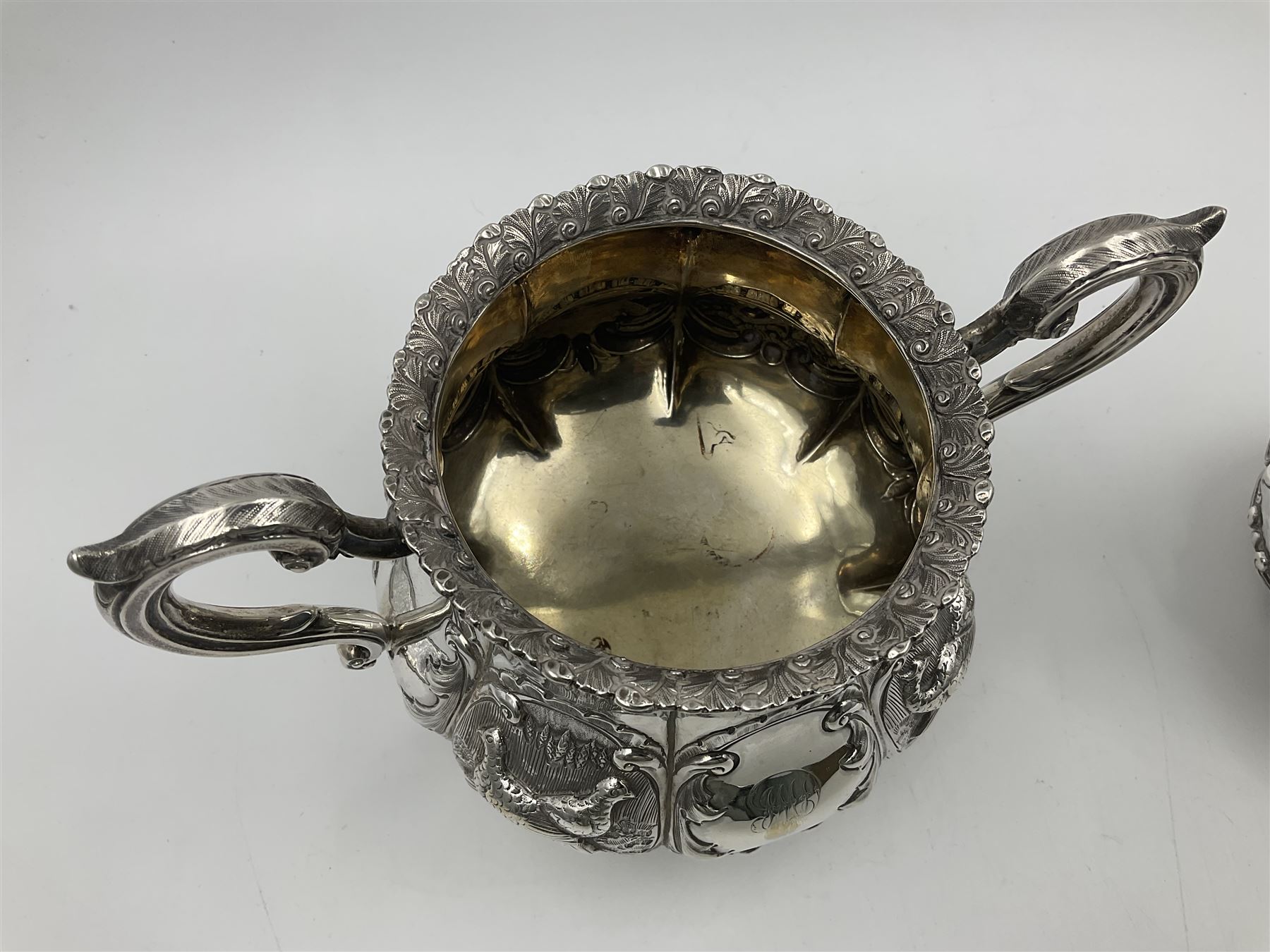 Victorian silver three piece tea service, comprising teapot, twin handled open sucrier, and milk jug, each of bellied form with acanthus capped scroll handles, the sides embossed with alternating scroll edged vacant panels and panels containing a pair of birds, upon four palmette feet, the teapot with ivory insulators to handle, and bird finial to the hinged domed cover, hallmarked William Hunter & Son, London 1861, teapot H19cm, including handles sucrier H13.5cm, including handle milk jug H12cm

This item has been registered for sale under Section 10 of the APHA Ivory Act