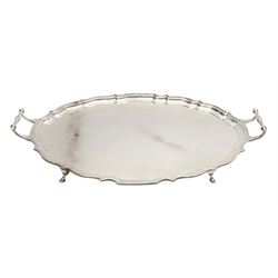Large early 20th century silver serving tray, of oval form with Chippendale type rim and twin handles, raised upon four hoof feet, hallmarked Barker Brothers Silver Ltd, Birmingham 1931, including handles L51cm, weight 57.29 ozt (1782 grams)