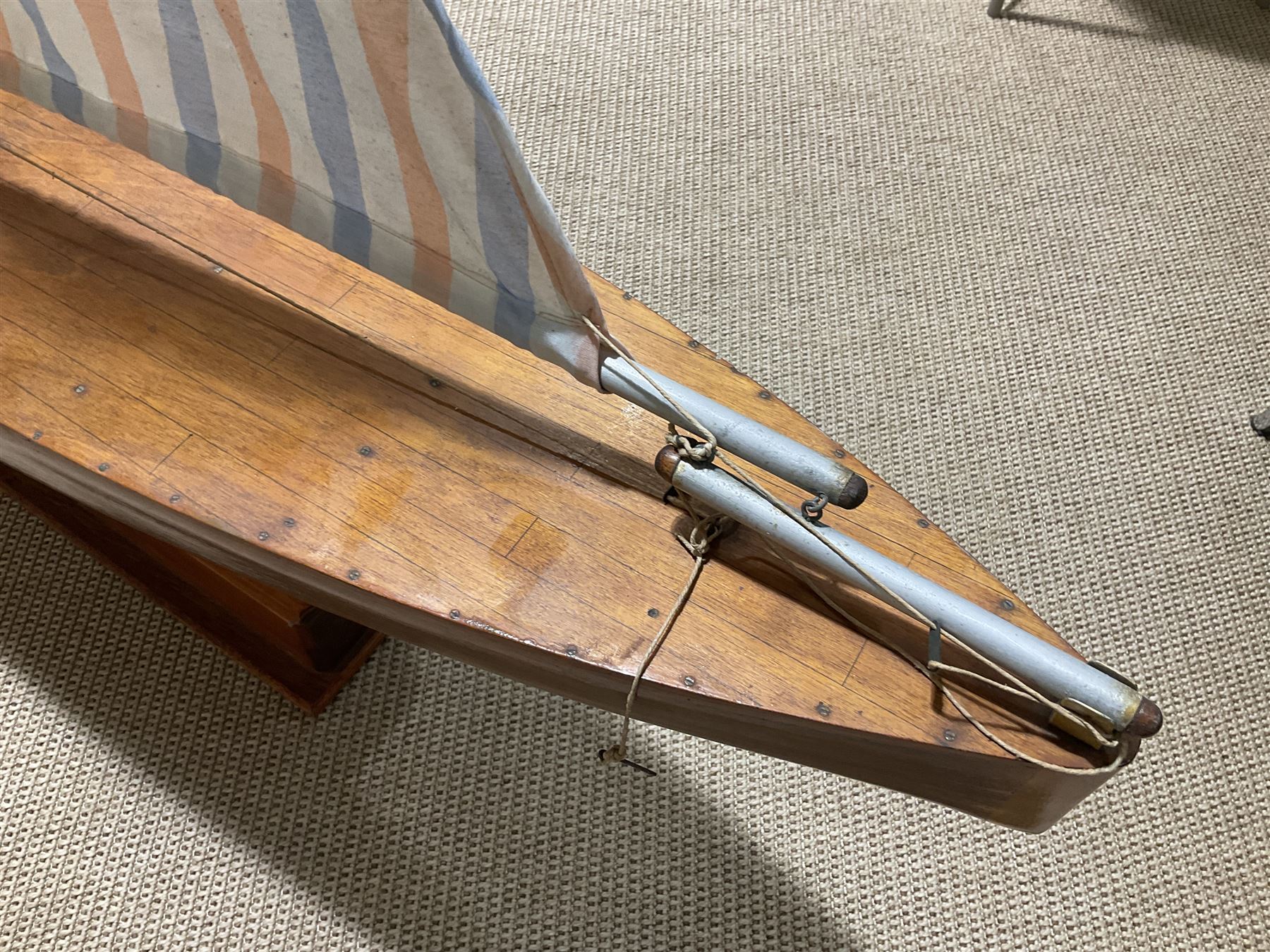 Large pond yacht with simulated planked mahogany deck, mahogany hull, wooden keel and stern fin and tubular aluminium mast with two sails; on wooden stand L131cm H on stand 177cm