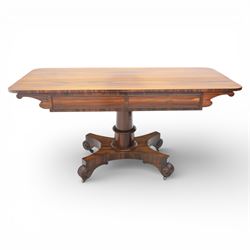 Victorian rosewood library table, rounded rectangular top with two frieze drawers with turned wooden knobs, quatriform base with scrolled ends terminating in brass castors  