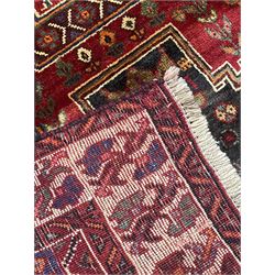Persian Shiraz red ground rug, the field decorated with various motifs, urns, flower heads and tree of life motifs, enclosed by rectangular bands with geometric decoration, floral repeating border