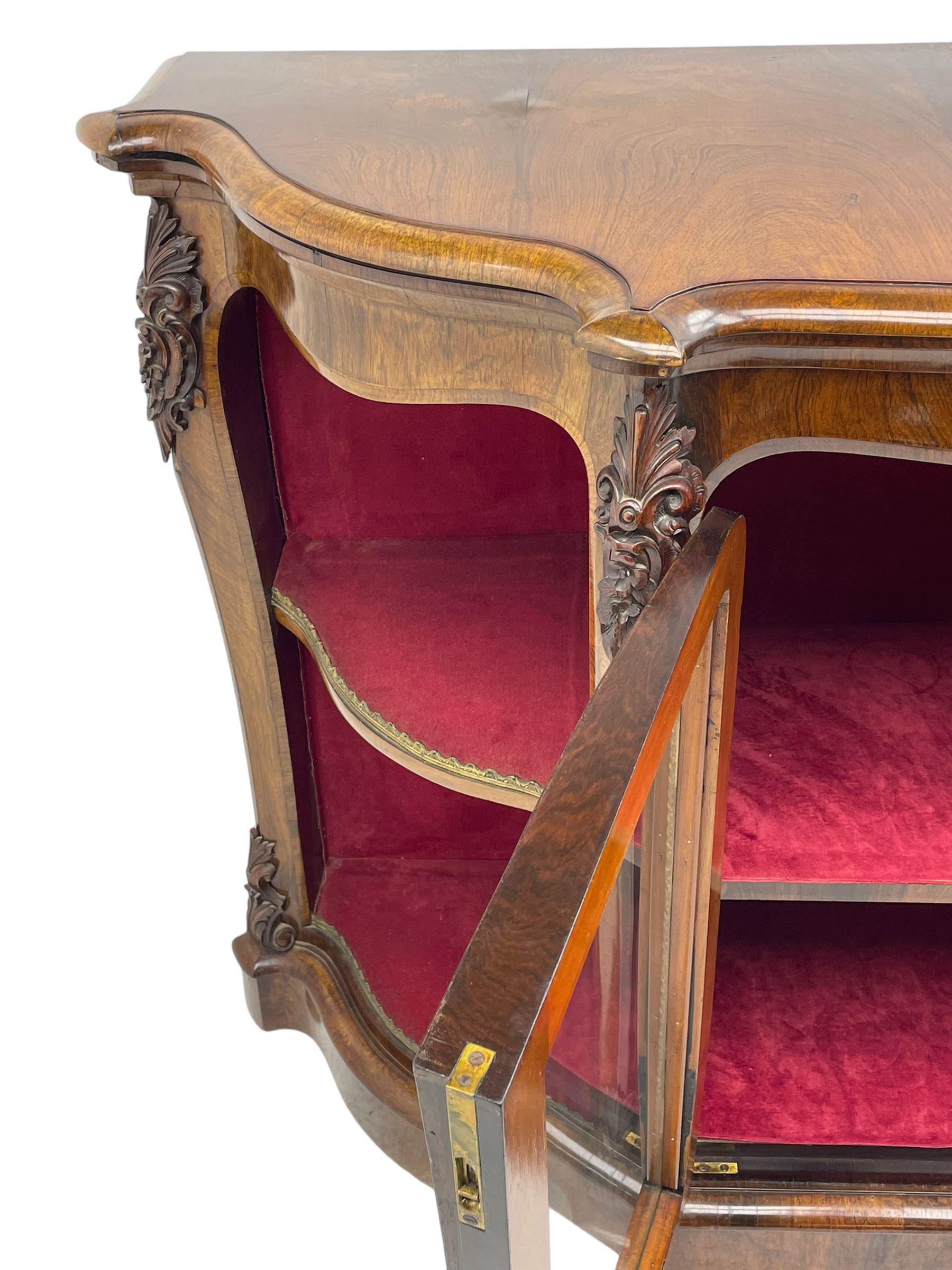 19th century rosewood buffet credenza, bombe form with shaped and moulded top, two central glazed doors with foliate moulded gilt slips, the red fabric-lined interior fitted with a single shelf, flanked by open shelves with raised gilt metal lips, the uprights decorated with shell and flower head carved cartouche mounts, acanthus leaf scroll carved lower mounts, on shaped and moulded plinth base 