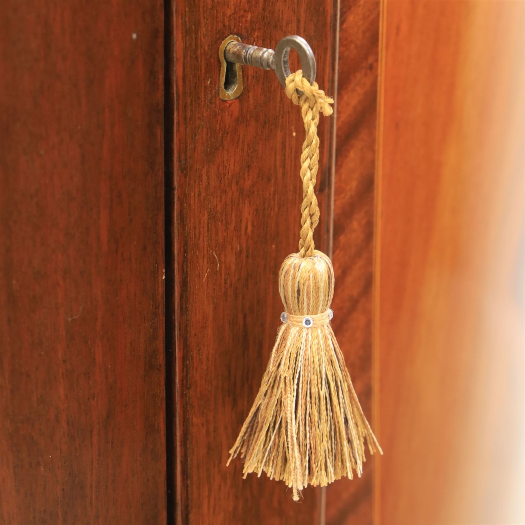 Edwardian inlaid mahogany cylindrical corner hall-robe, projecting cornice, figured veneer and crossbanded door, enclosing hanging hooks and shelf, raised on a plinth base with bracket feet