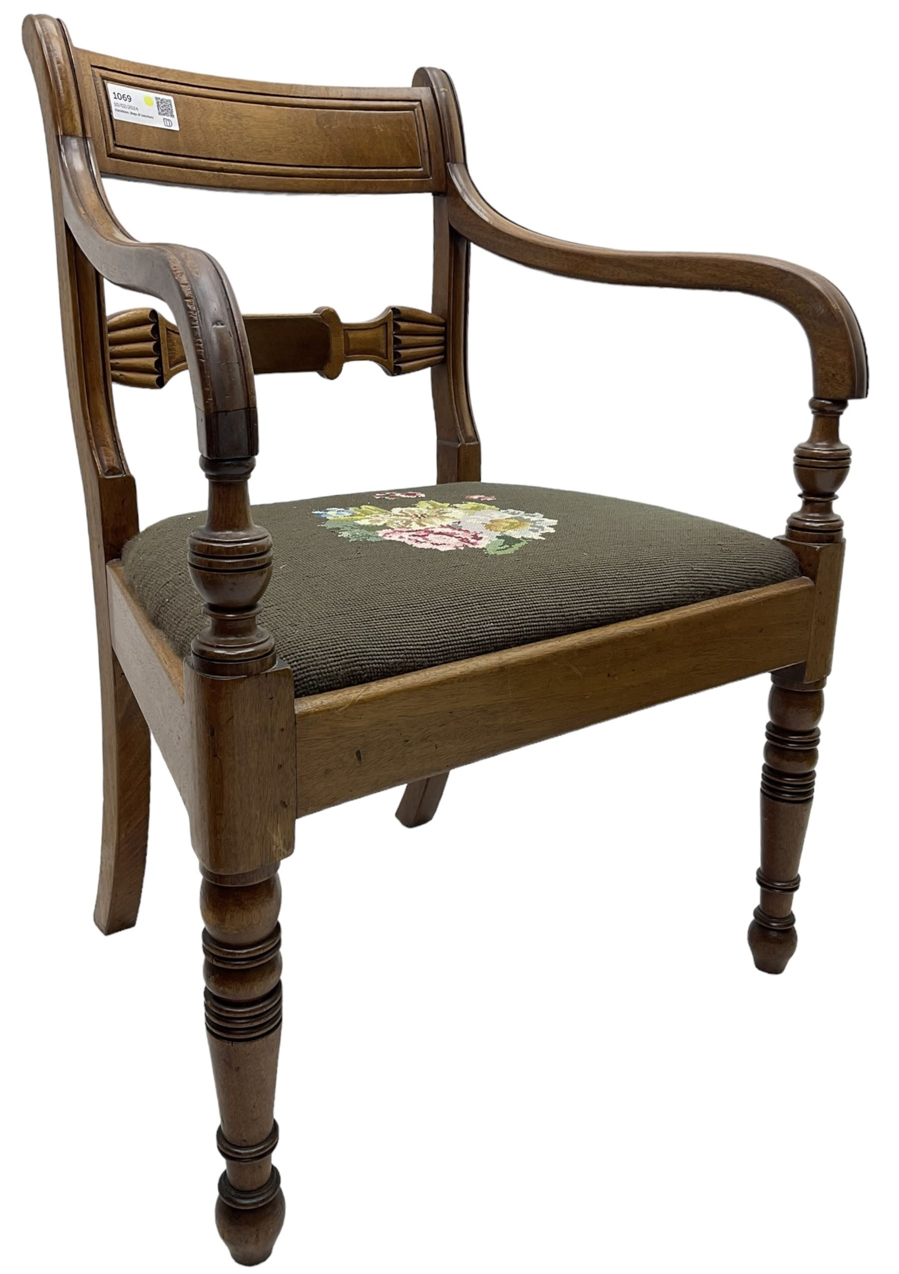 Regency mahogany elbow chair, carved shaped central back bar, over drop-in seat upholstered in floral needlework, raised on ring turned front supports