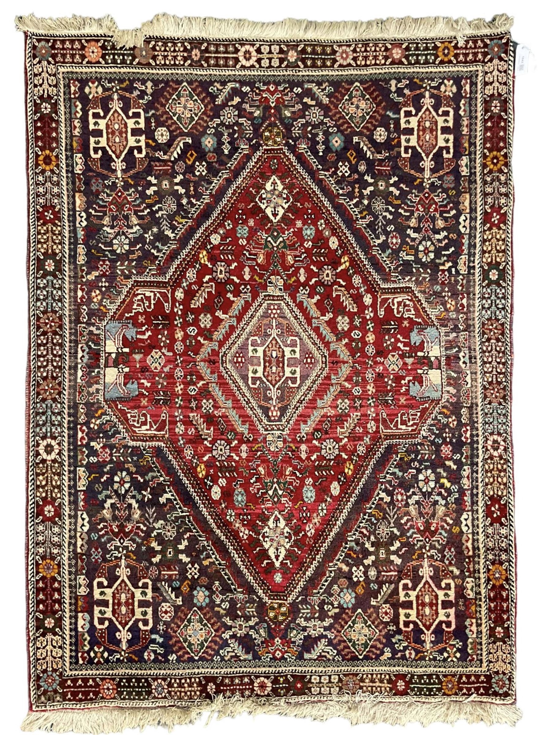 Persian Heriz crimson ground rug, field with large central lozenge surrounded by stylised plant motifs in a mauve background, guarded border with repeating foliage