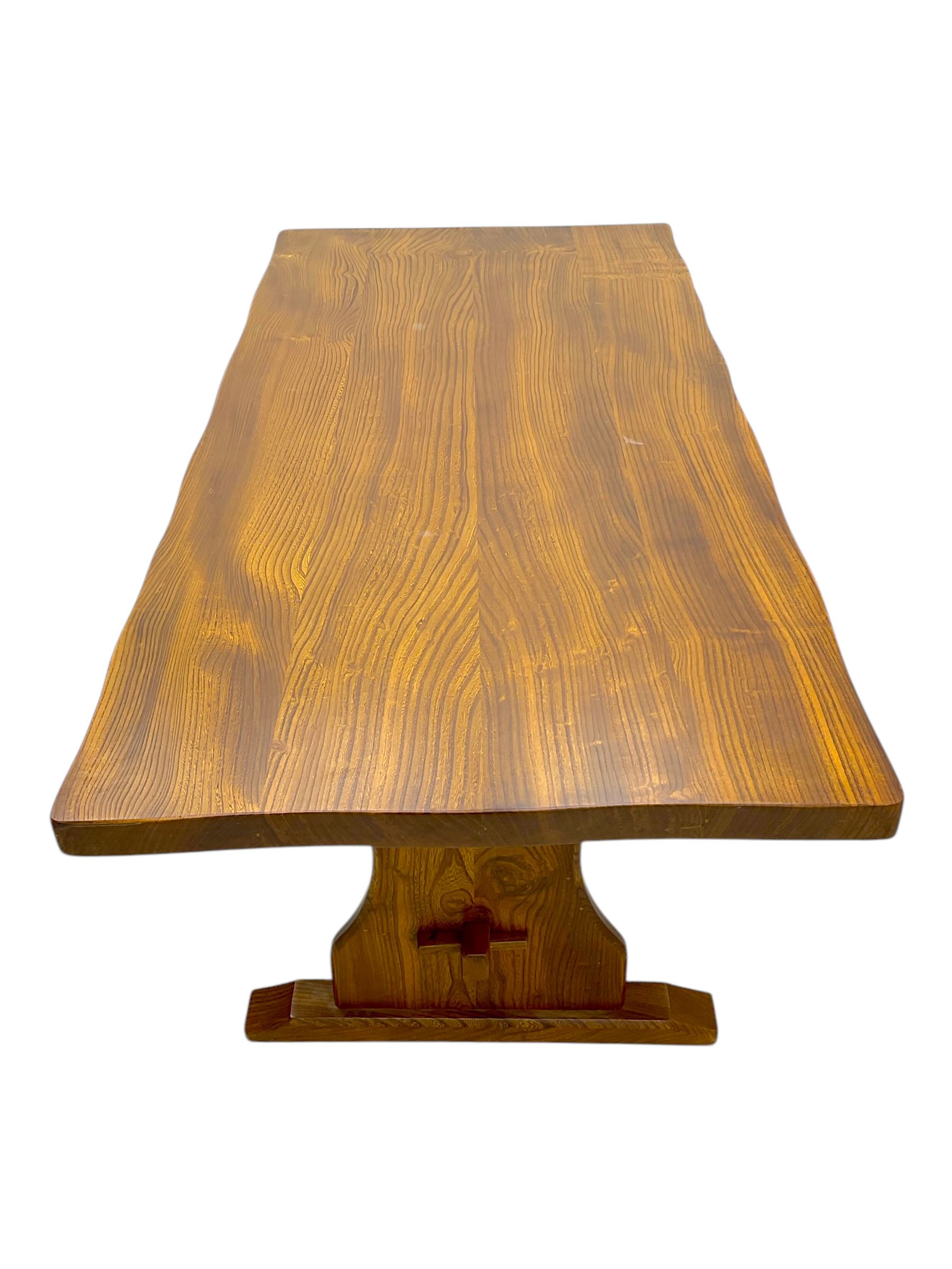 Late 20th century oak trestle table, rectangular top with naturalistic edge, supported by two curved pedestal bases united by central stretcher, on block feet