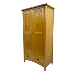 Contemporary light oak double wardrobe, projecting cornice over two panelled doors enclosing hanging rail and shelf, above full-width drawer, on shaped stile supports