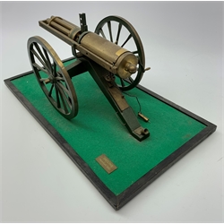 Scratch built brass model of an 1861 Gatling Gun with rotating barrels, hinged cover revealing mechanism, on metal bound wooden spoked wheels and rectangular base L47cm H22cm
