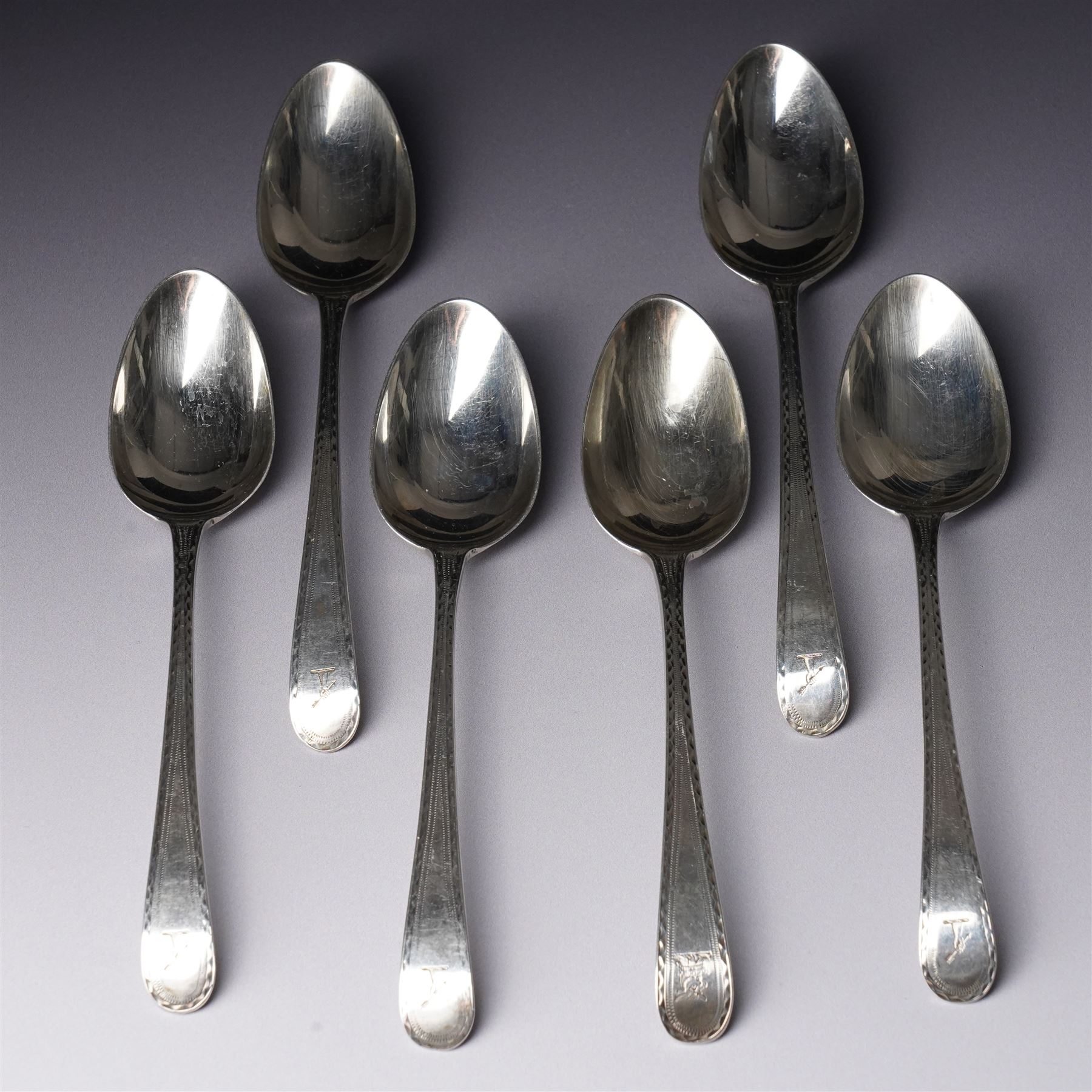 Set of six George III silver dessert spoons with bright cut stems and engraved with a crest London 1783 Maker Hester Bateman