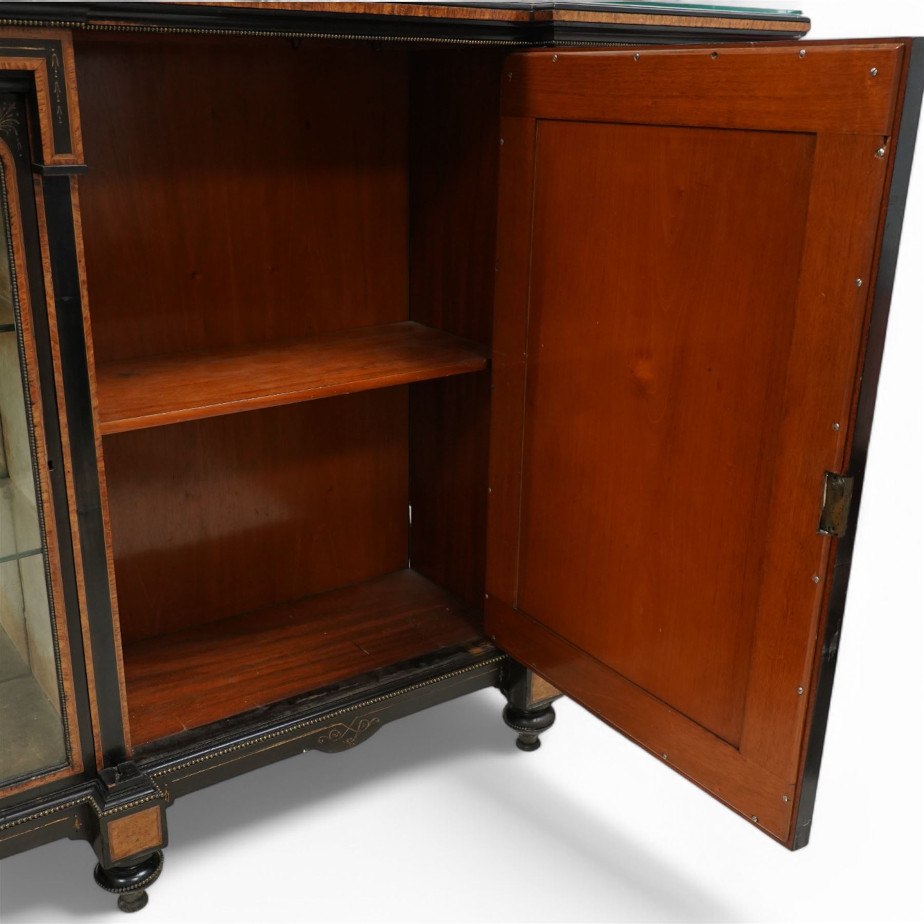 Victorian amboyna and ebonised credenza with glass top, the freeze fitted with two Wedgewood plaques and brass beading above crossbanded arched glazed mirror door flanked by two glazed cabinet doors with two removable glass shelves between four gilt brass reeded floral columns, supported on bun style feet
