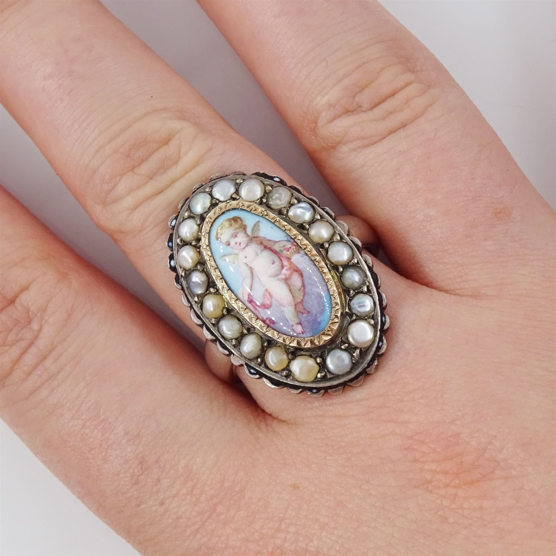19th century French silver enamel portrait ring, set with an oval hand painted panel of a cherub, with split pearl surround