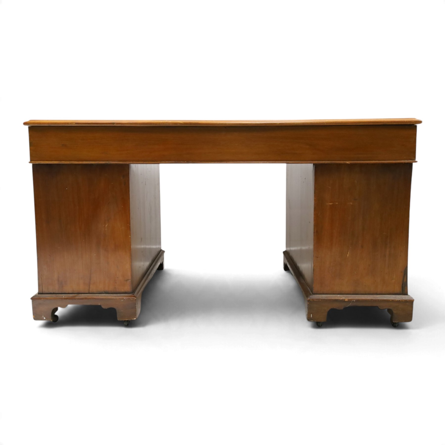Late Victorian mahogany desk with red leather top, rectangular top with inset toold red leather writing surface, central long frieze drawer flanked by two short drawers, above pedestal with three graduating drawers with ring pull handles, on moulded plinth bases raised on castors