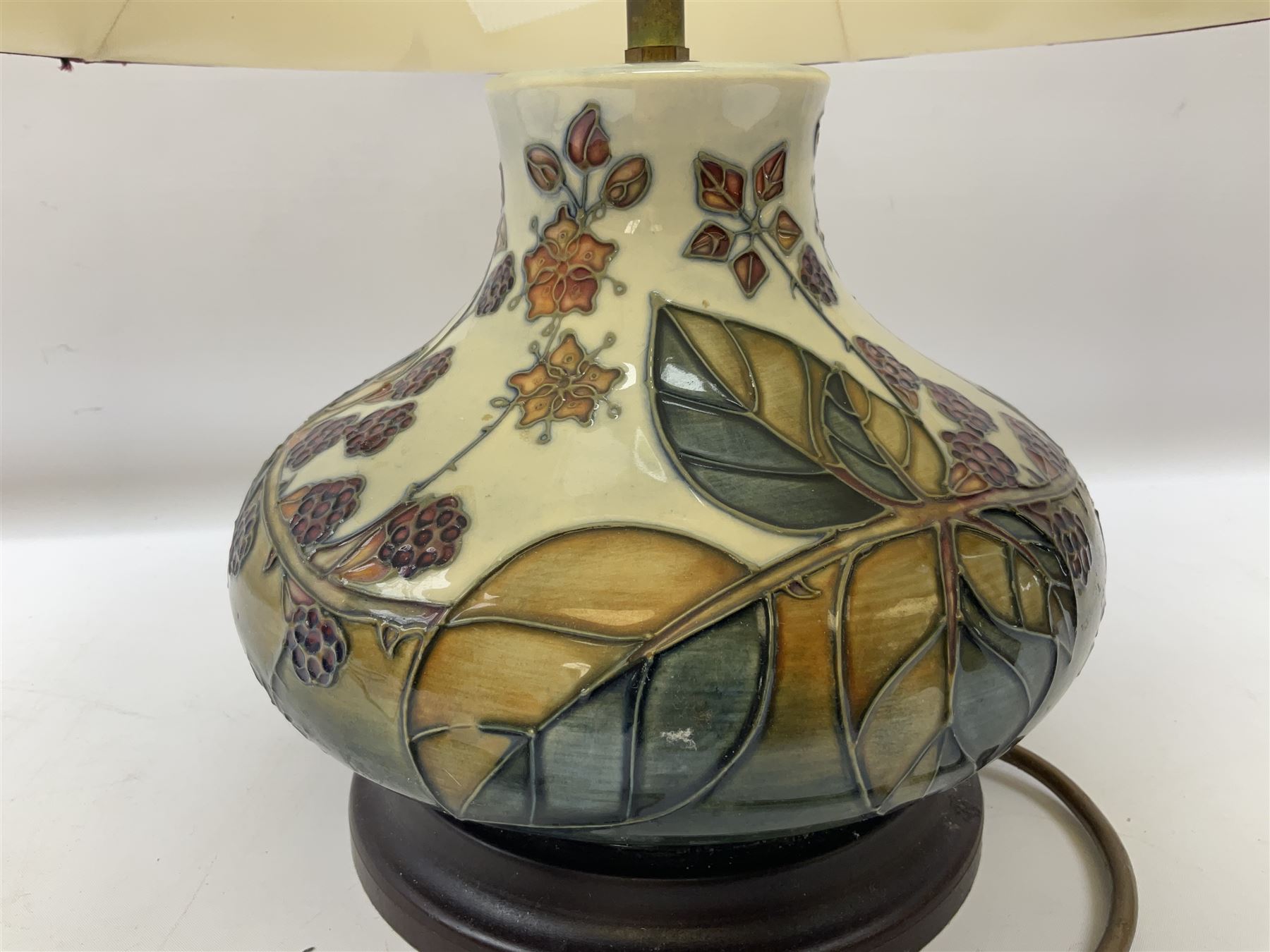 Moorcroft table lamp of squat baluster form, decorated in the Autumn Blackberry, with Moorcroft cream fabric shade with gold, green and red piping, overall H38cm