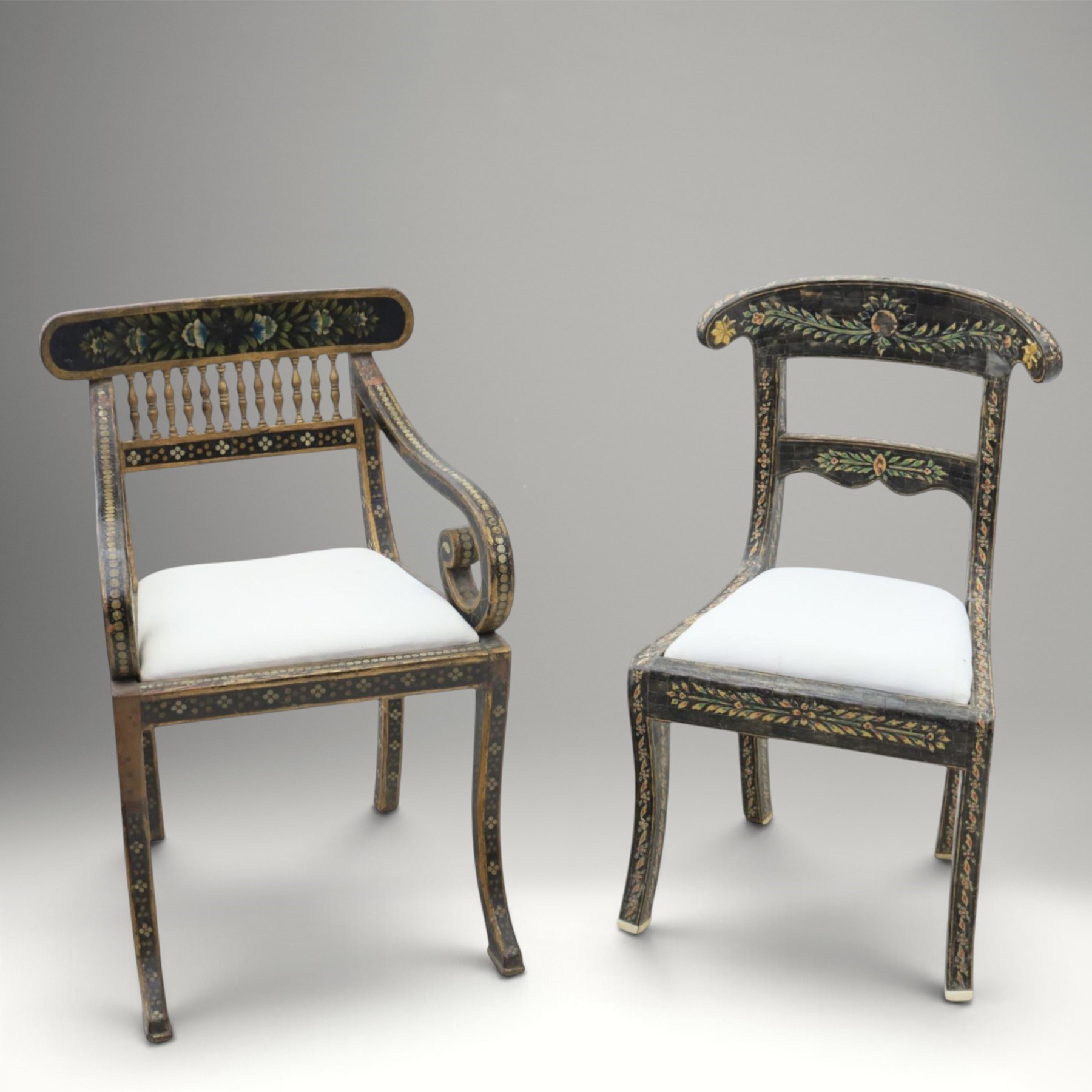 Early 20th century Anglo-Indian painted and inlaid armchairs, each with shaped top rail decorated with polychrome floral motifs above turned spindle galleries, shaped open arms and upholstered seats, on square supports with similar painted decoration