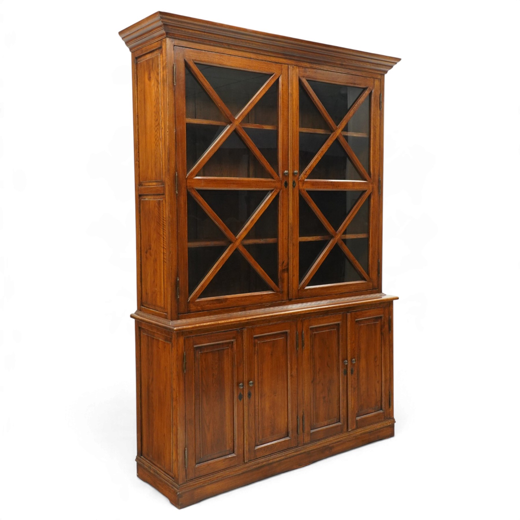 OKA - Glazed bookcase dark oark cabinet, the top with projecting cornice above astragal style glazed doors metal turned knobs, enclosing adjustable full length shelving, the lower half with two sets of twin cabinet doors housing fixed shelving, raised on a moulded plinth base  